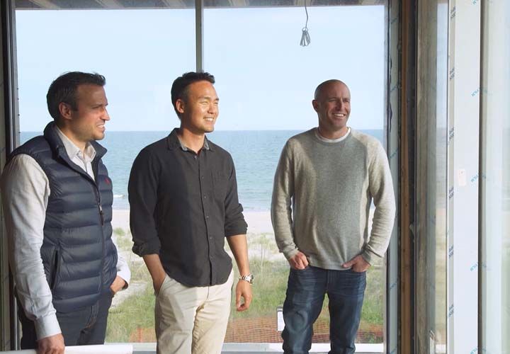 three men smiling and looking out a window