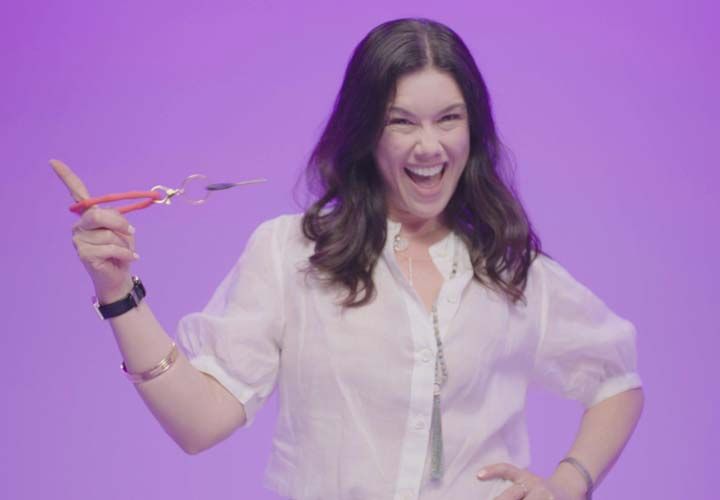 a smiling woman spinning a set of keys standing in front of a purple bacground