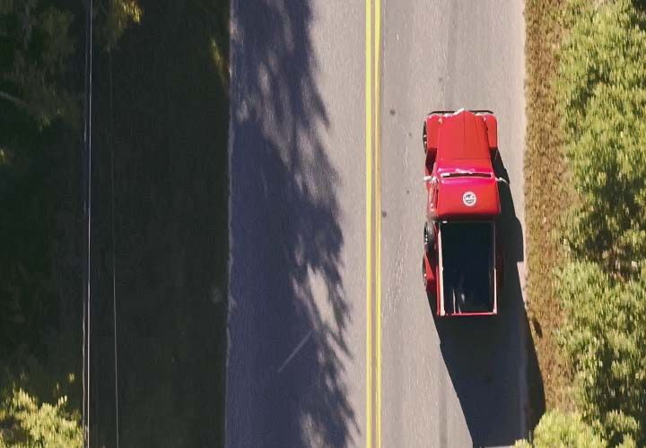 overhead image of an old red truck driving down the road