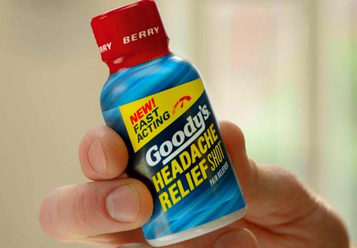 a hand holding a bottle of Goodys Headache relief shot
