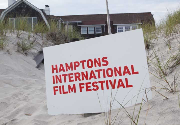 a Hamptons International Film Festival sign in the sand at a beach