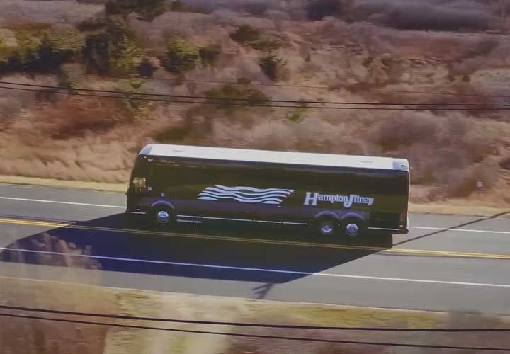 a drone image of a Hampton Jitney bus driving on a street near the beach