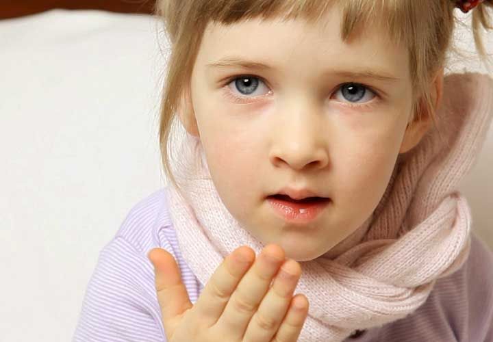 a young girl covering her mouth after a cough