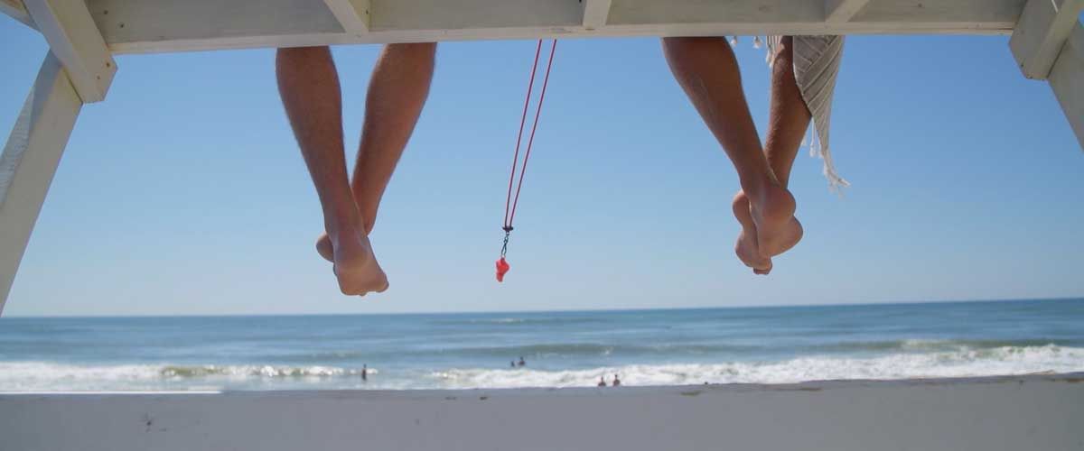two lifeguards feet dangling down from a lifeguard chair