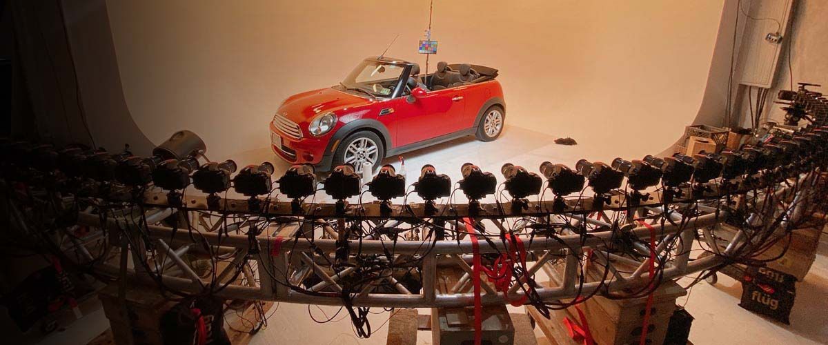 a red Mini Cooper on stage being surrounded by cameras